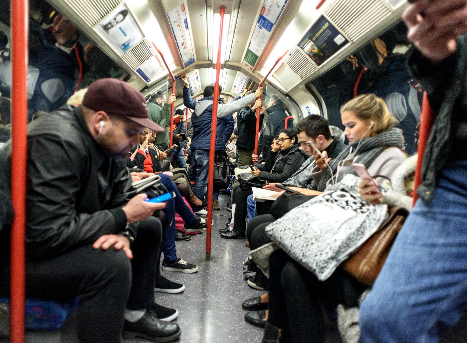 Various mixed people riding on a London Underground tube train in their carriages both sitting and standing underground 0345592798