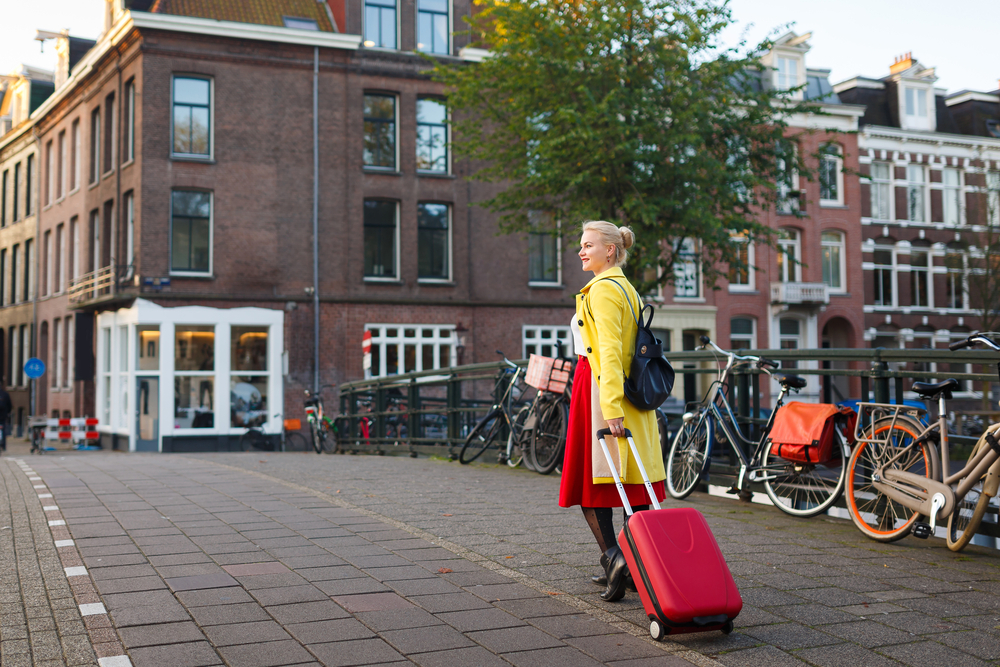 Turistka se v centru Amsterdamu očividně těší, jak její dočasné bydlení přispěje místním aktivitám turistka 730035460